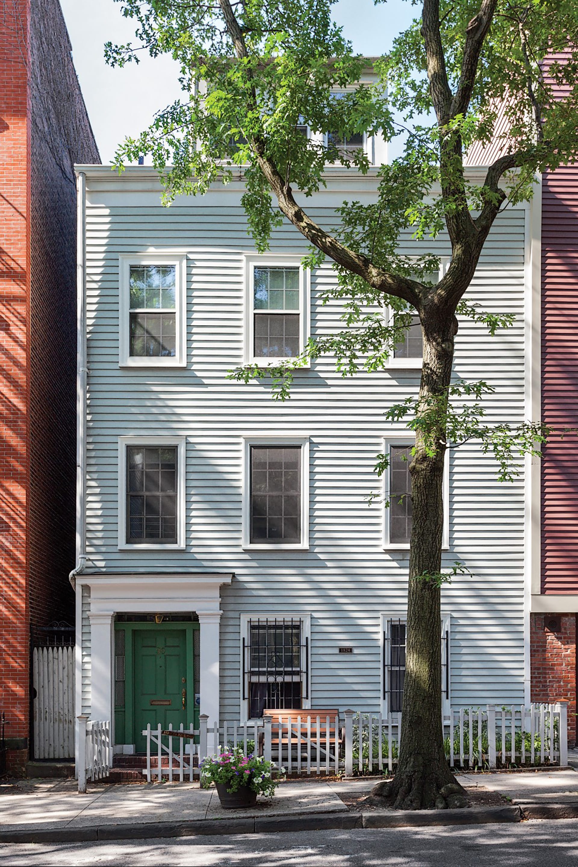 Front façade of a Brooklyn townhome with a green front door, white trim, and light blue siding.